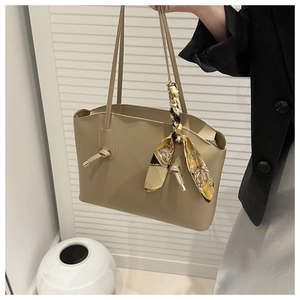 Detail of khaki leather tote bag featuring a decorative printed silk scarf and knot accents