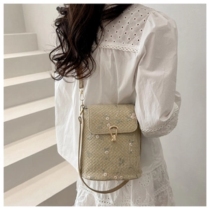 Detail of straw crossbody bag with pink floral embroidery and gold metal buckle