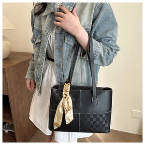 Detail of black tote bag with checkered panel and scarf wrapped on handle