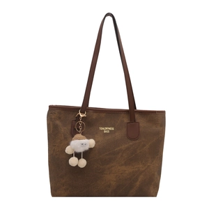 Classic dark brown leather tote bag for women with a plush white pendant and golden logo