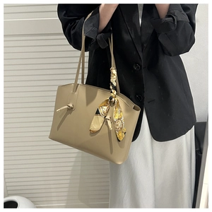 Khaki tote bag detail with silk scarf handle decoration on a stylish commuter shoulder bag