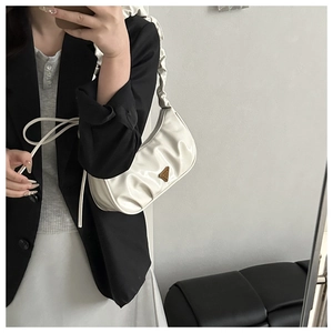 Detail of white pleated hobo bag with metallic triangle buckle and soft leather texture