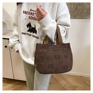 Dettaglio della borsa tote in velluto marrone con stampa orso e manici color kaki