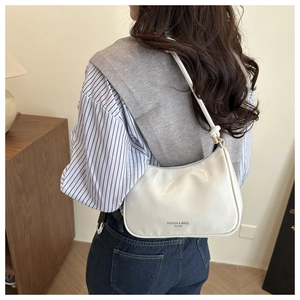 Close-up of a white minimalist shoulder bag featuring elegant letter print and fine texture