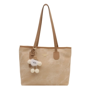 Large beige tote bag with dark brown leather straps and a cute plush doll keychain
