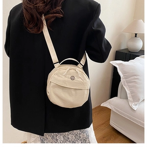 Cream round canvas shoulder bag shown on model in cozy interior setting for daily outfit