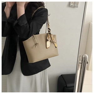 Detail of khaki tote bag with knotted texture and elegant silk scarf on handle