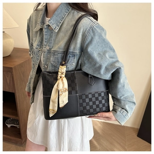 Detail of black patchwork tote bag with checkered pattern and silk scarf handle decor