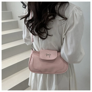 Detail of light pink shoulder bag with a metal bow buckle on a white staircase