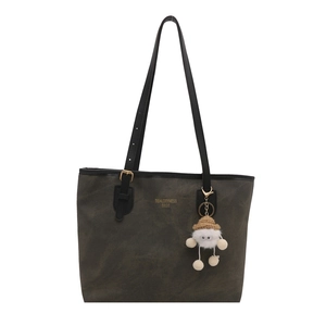 Large brown leather tote bag with long black handles and cute plush charm on white background