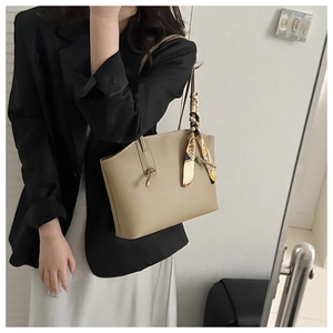 Close-up of beige leather tote bag with elegant printed scarf wrapped on handle