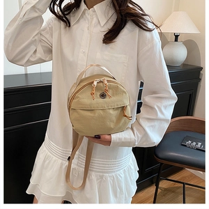 Detail of beige round nylon bag featuring metal handles and functional zipper drawstrings