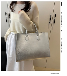 Close-up of silver tote bag featuring a high-gloss crocodile embossed texture and dual handles
