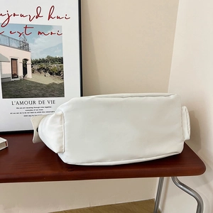 Minimalist white nylon messenger bag with large capacity shown on a dark wooden table