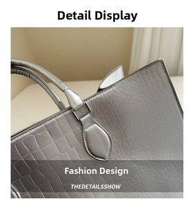 Close-up of crocodile-embossed silver tote bag with metallic handle attachment details