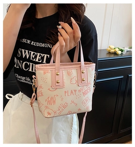 Detail of color-block tote bag with cute cartoon prints and golden metal hardware