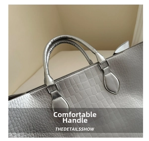 Detailed macro view of silver faux crocodile embossed leather handbag with sturdy handles