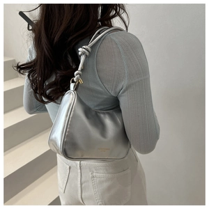 Detail of silver crescent bag featuring tied knot strap and fashion bags logo text