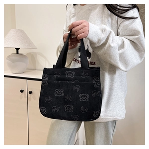 Dettaglio della borsa in velluto a coste nero con ricamo orsetto e scritta Smile