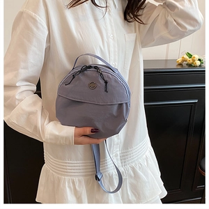Detail of blue round crossbody bag with adjustable strap and drawstring detail