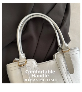 Detailed close-up of silver tote bag handle with golden metal rings and neat stitching