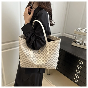 Detail showing high-capacity cream tote bag with grey M-letter monogram print and long handles