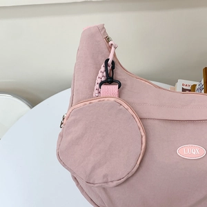 Pink nylon crossbody bag with mini round pouch and rubber logo on white background