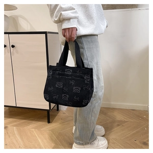 Modella con borsa in velluto a coste nera con orsetto bianco e scritta Smile