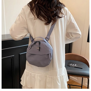 Detail of lavender nylon mini round bag with adjustable strap worn as a backpack