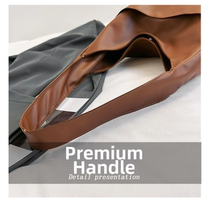 Detail of wide brown leather handle with fine stitching and magnetic buckle closure