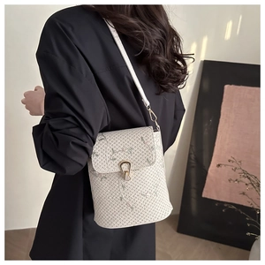 Détail de la broderie florale et du fermoir métallique sur un sac seau tressé