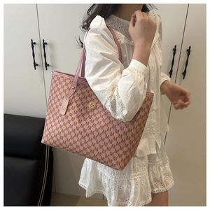 Detail of a large pink tote bag with M-pattern print and gold emblem on white dress