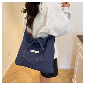 Detail of denim tote bag showing bow decoration and contrast outer pocket texture