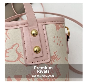 Detailed macro view of gold rivets and pink graffiti pattern on the white bucket bag