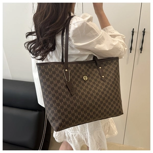 Macro shot of dark brown monogram tote bag with gold metal logo and leather detail