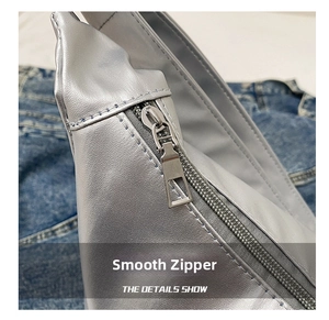 Détail d'une fermeture éclair argentée sur un sac cabas brillant sur fond en denim