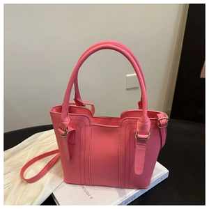 Detailed view of the bright pink tote bag with cylindrical handles and adjustable strap