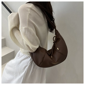 Detailed close-up of brown litchi grain leather and gold logo on the hobo shoulder bag
