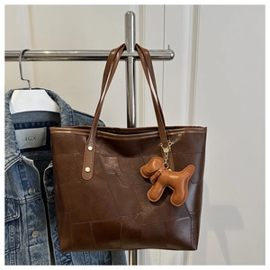 Détail du sac cabas marron foncé avec texture géométrique et charm de chiot