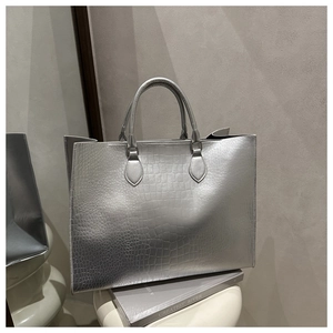 Detail of silver crocodile pattern tote bag with metallic finish and round top handles