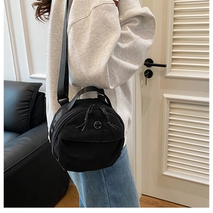 Model wearing a black round nylon crossbody bag showing size and fit for women