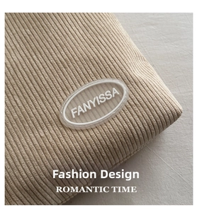 Detail shot of beige corduroy tote bag showing the textured fabric and logo patch