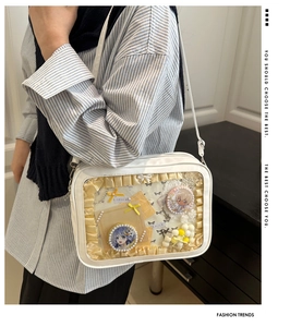 Detail of white ita bag with transparent window displaying anime pins and postcards