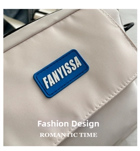 Close-up of FANYISSA logo on cream nylon crossbody bag with detailed fabric texture