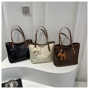 Détail de sacs cabas en noir, crème et café avec des charms de chiots design élégants