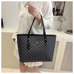 Detail of the monogram M print and gold logo hardware on a large tote bag