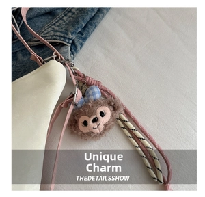 Detail of soft ShellieMay plush charm with blue plaid bow attached to a backpack