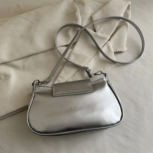 Silver metallic rectangular crossbody bag with minimalist flap design on cream fabric
