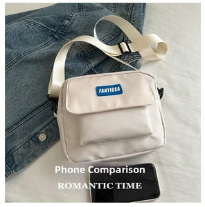 Mini off-white canvas crossbody bag next to a smartphone showing portable compact size