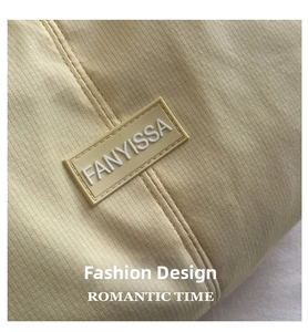 Close-up of FANYISSA rubber label on pale yellow nylon striped crossbody bag
